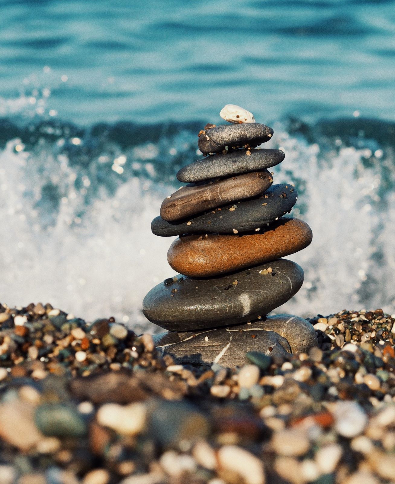 pebbles stacked on a beach with waves crashing in the background